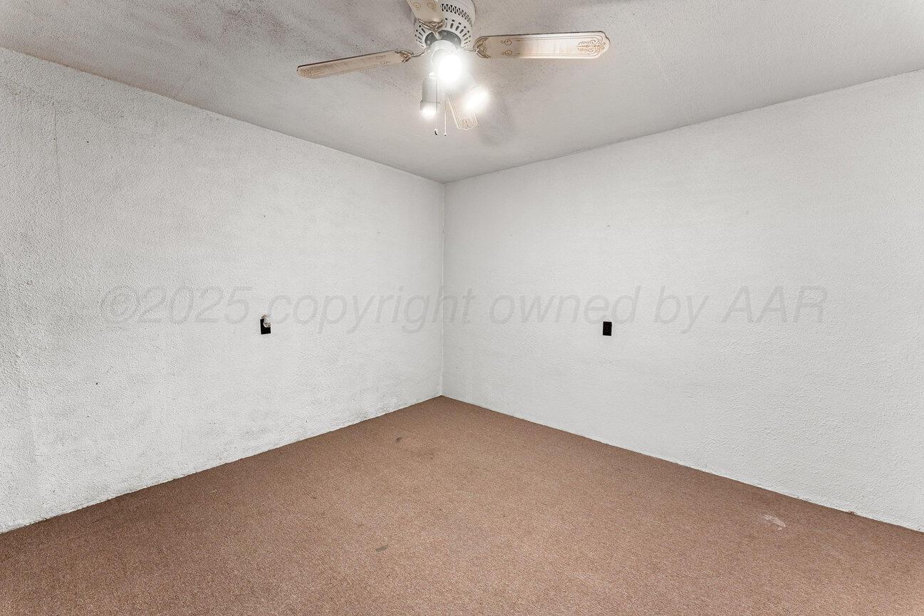 1133 Elmore Street Borger, TX 79007 - Photo 24 of 43 an empty room with a chandelier fan and windows