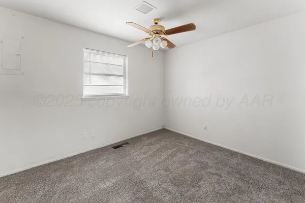 an empty room with a window and a fan