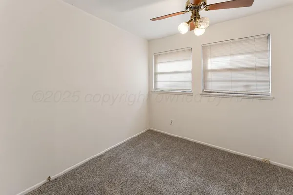 an empty room with a window and ceiling fan