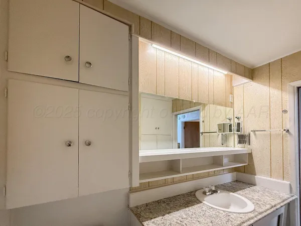 a bathroom with a granite countertop sink and a mirror