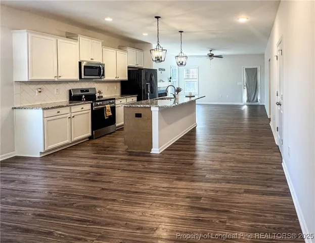 a kitchen with stainless steel appliances granite countertop a refrigerator a stove a sink dishwasher and a fireplace with wooden floor