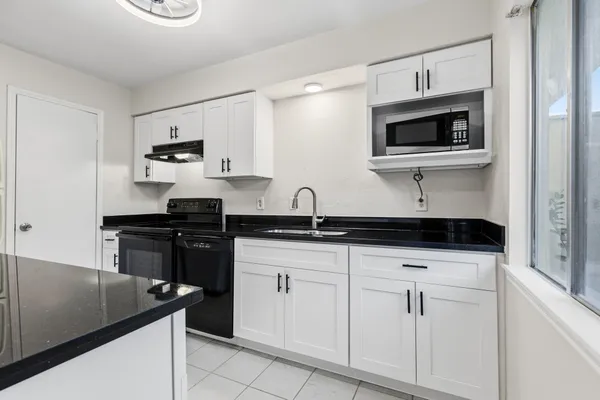 a kitchen with white cabinets and appliances