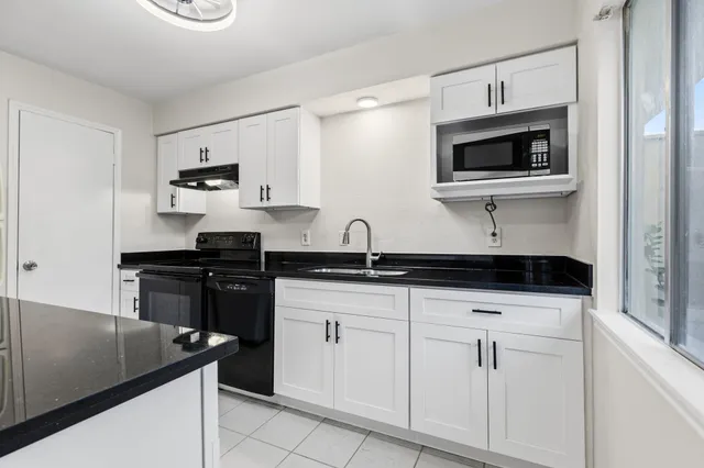a kitchen with white cabinets and appliances