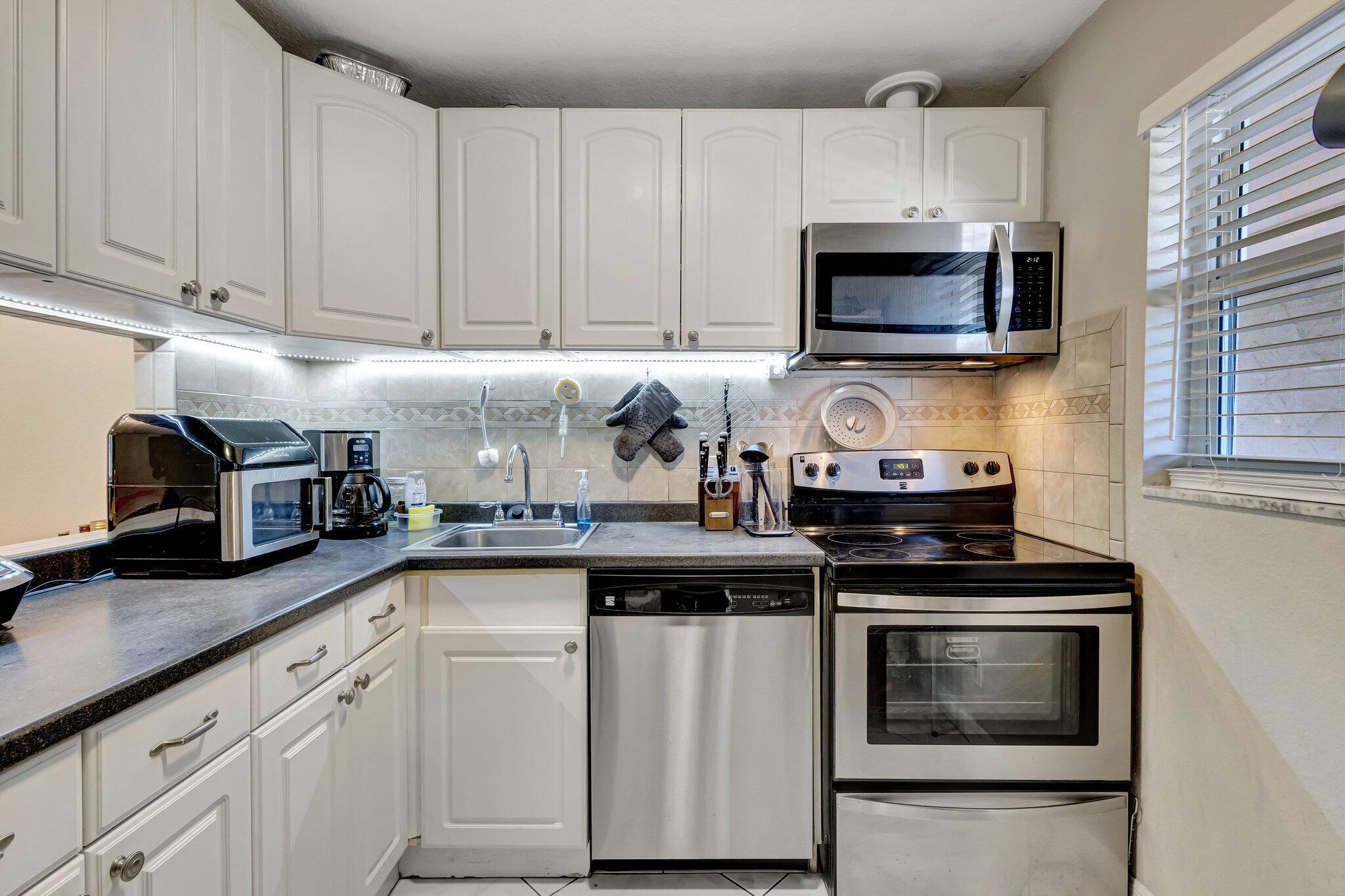 12012 Greenway Circle South, Unit 205 Royal Palm Beach, FL 33411 - Photo 11 of 36 a kitchen with white cabinets and appliances