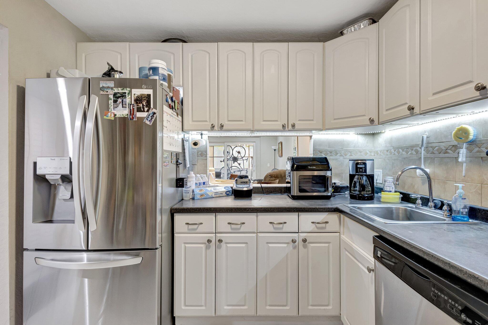 12012 Greenway Circle South, Unit 205 Royal Palm Beach, FL 33411 - Photo 13 of 36 a kitchen with stainless steel appliances granite countertop a refrigerator sink and white cabinets