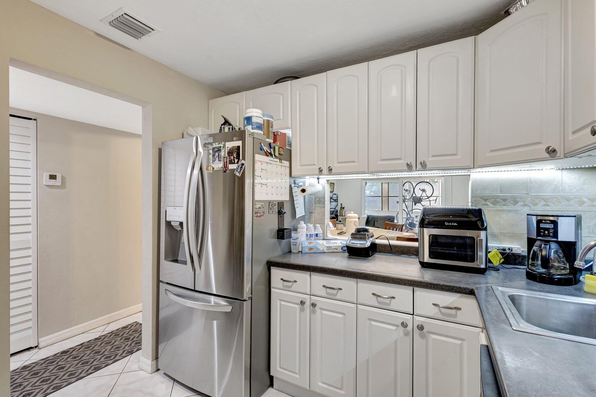 12012 Greenway Circle South, Unit 205 Royal Palm Beach, FL 33411 - Photo 14 of 36 a kitchen with stainless steel appliances a refrigerator a stove a microwave and cabinets