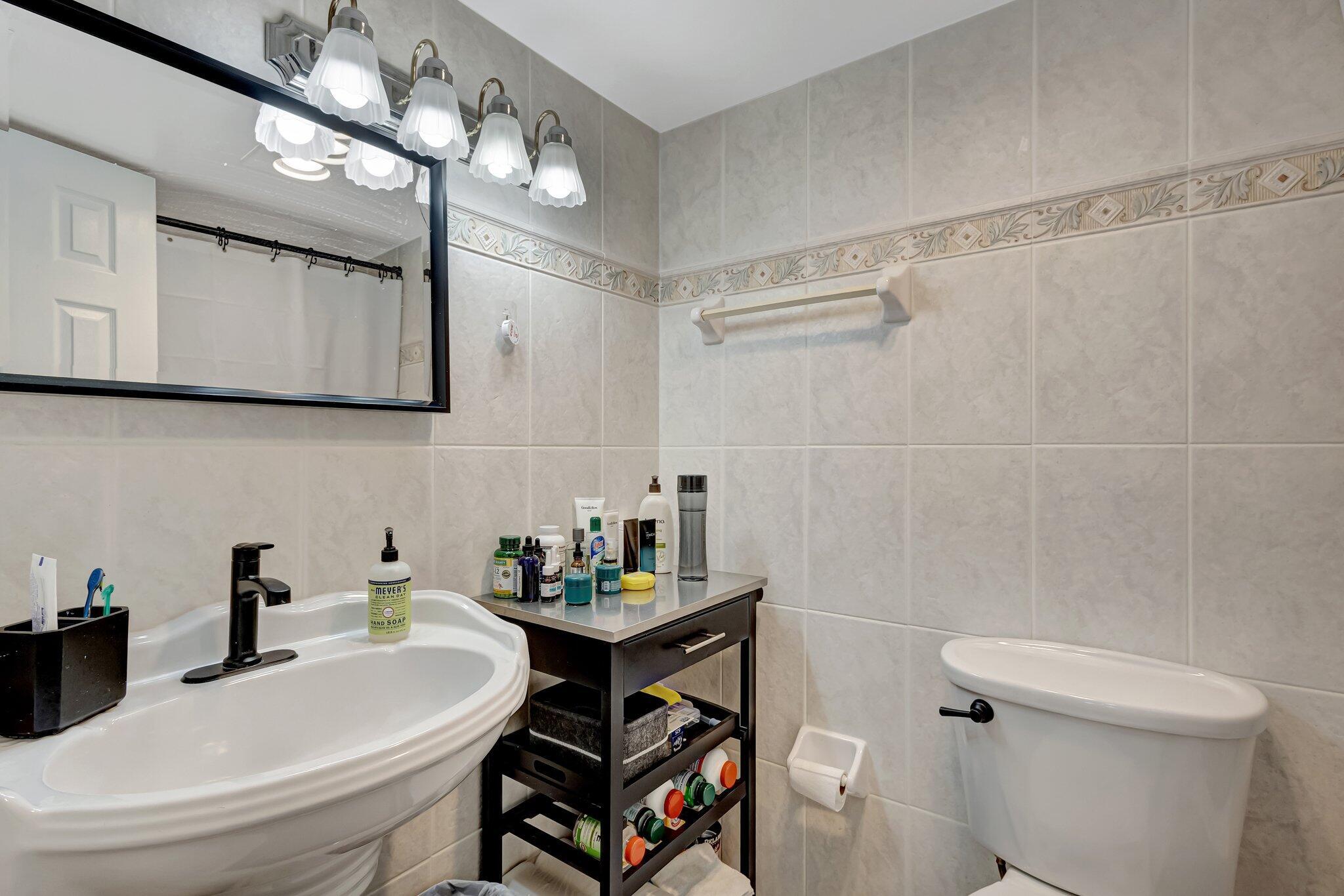 12012 Greenway Circle South, Unit 205 Royal Palm Beach, FL 33411 - Photo 28 of 36 a bathroom with a sink a toilet and a mirror