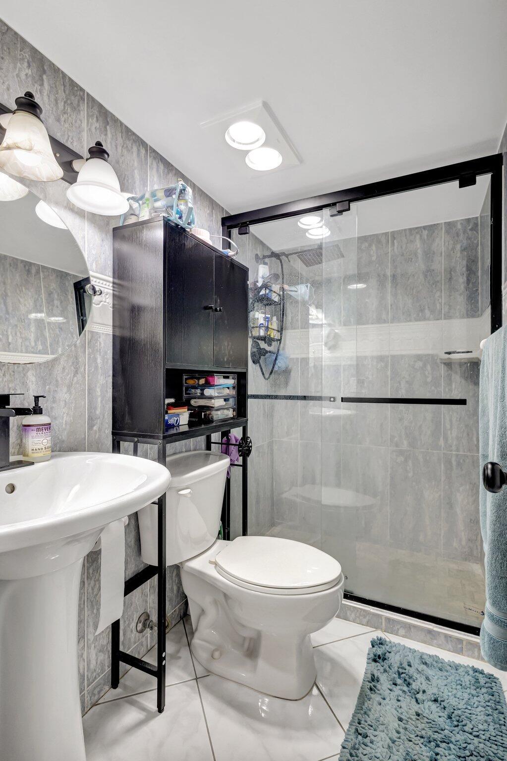 12012 Greenway Circle South, Unit 205 Royal Palm Beach, FL 33411 - Photo 34 of 36 a bathroom with a sink a toilet a mirror and shower