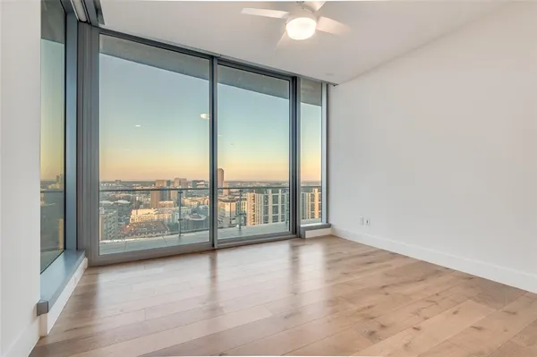an empty room with wooden floor and windows with city view
