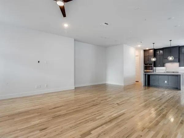 a view of kitchen and empty room with wooden floor