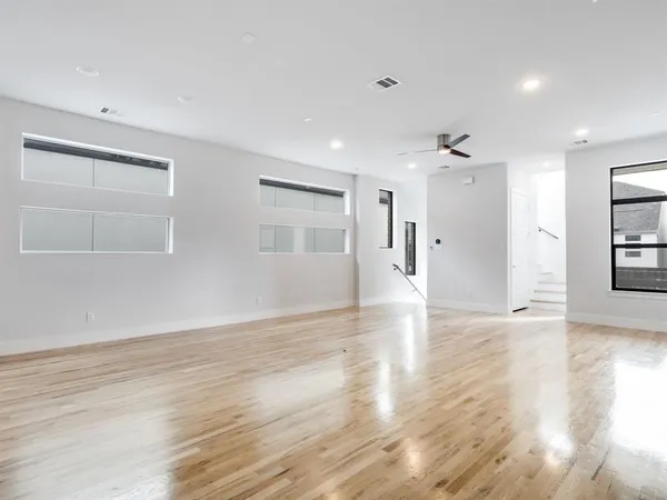 a view of an empty room with window and wooden floor