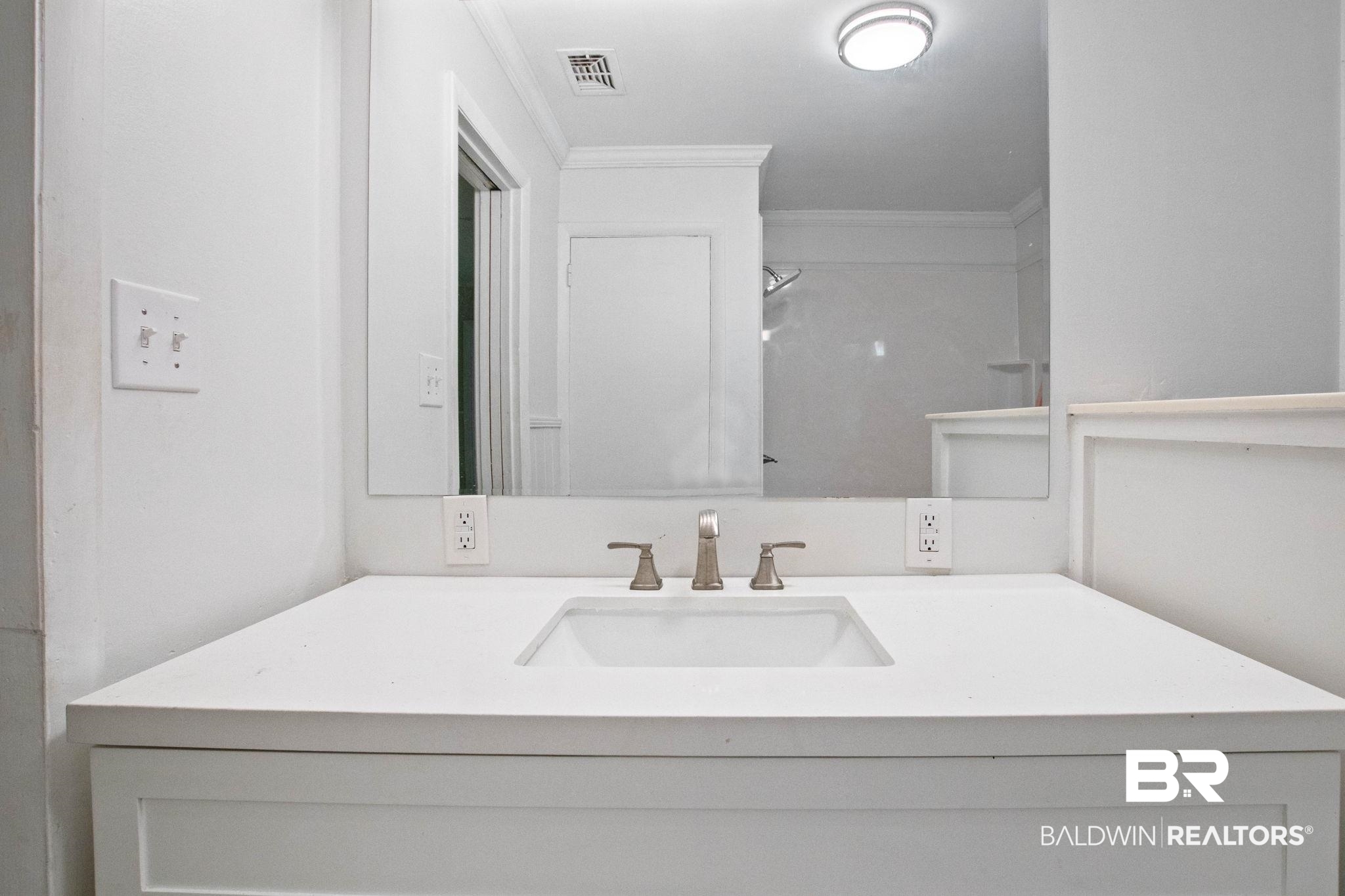 384 Old Bratt Road Atmore, AL 36502 - Photo 49 of 64 White vanity with an integrated rectangular sink, brushed nickel faucet, and a large wall-mounted mirror