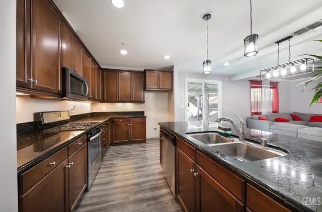 a kitchen with stainless steel appliances granite countertop a sink a stove and a wooden floors