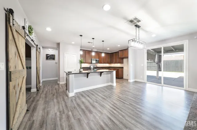 a large kitchen with stainless steel appliances refrigerator a stove and wooden floor