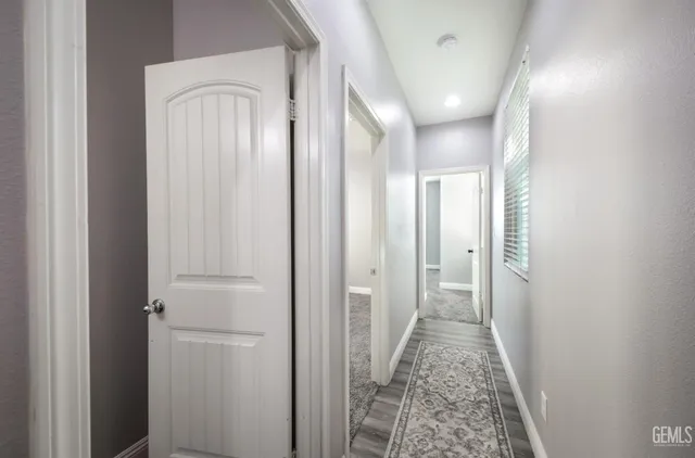 a view of a hallway with wooden floor and a bathroom