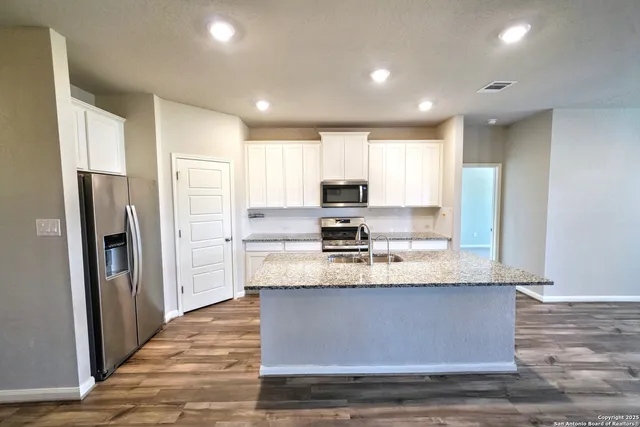 a large kitchen with stainless steel appliances granite countertop a stove refrigerator and cabinets