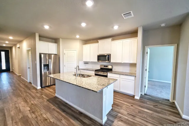 a kitchen with granite countertop white cabinets appliances and a sink