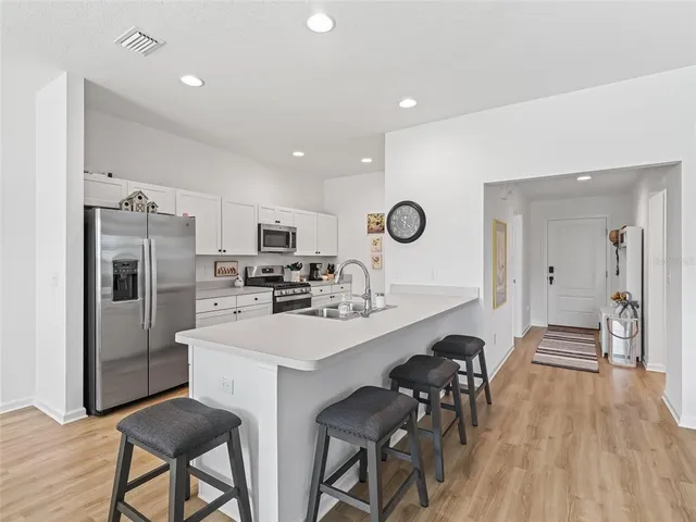 a kitchen with refrigerator a sink and chairs