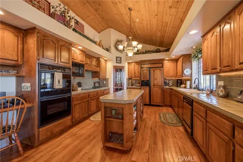 a kitchen with stainless steel appliances granite countertop a stove a sink dishwasher and a refrigerator with wooden floor
