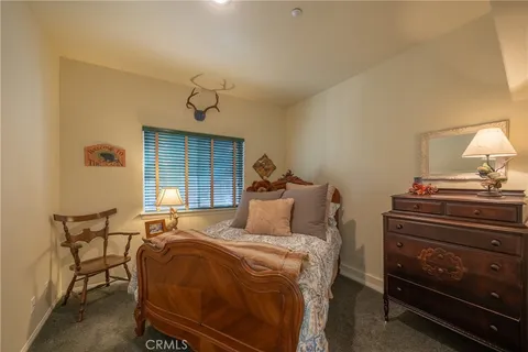 a bedroom with a bed and chair with the large windows