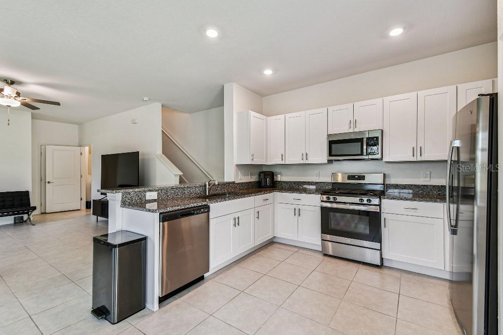 8331 Corner Pine Way New Port Richey, FL 34655 - Photo 19 of 41 a kitchen with stainless steel appliances granite countertop a stove top oven a sink and a refrigerator