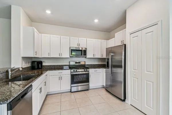 a kitchen with granite countertop white cabinets and stainless steel appliances