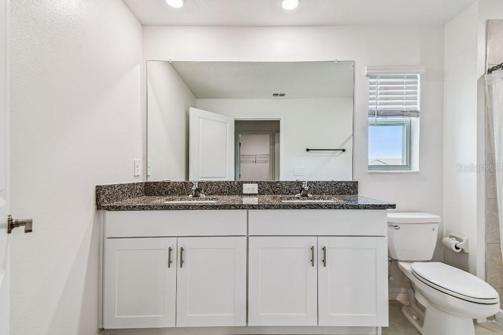 8331 Corner Pine Way New Port Richey, FL 34655 - Photo 34 of 41 a bathroom with a granite countertop toilet sink and mirror