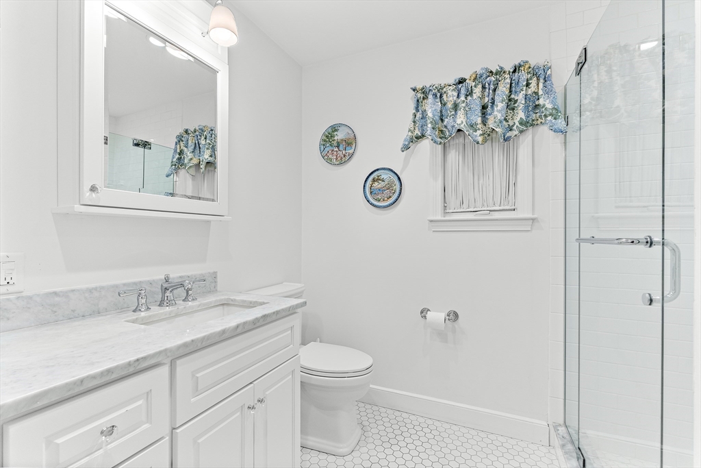 10 Viking Road Winchester, MA 01890 - Photo 19 of 42 a bathroom with a granite countertop sink a toilet and a mirror