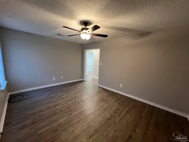 an empty room with wooden floor fan and windows