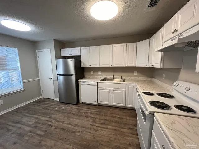 a kitchen with a refrigerator sink and white cabinets