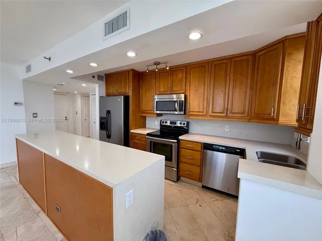 a kitchen with kitchen island a sink stainless steel appliances and cabinets