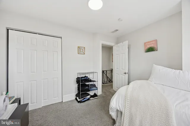 a bedroom with a bed a couch and a lamp on the dresser