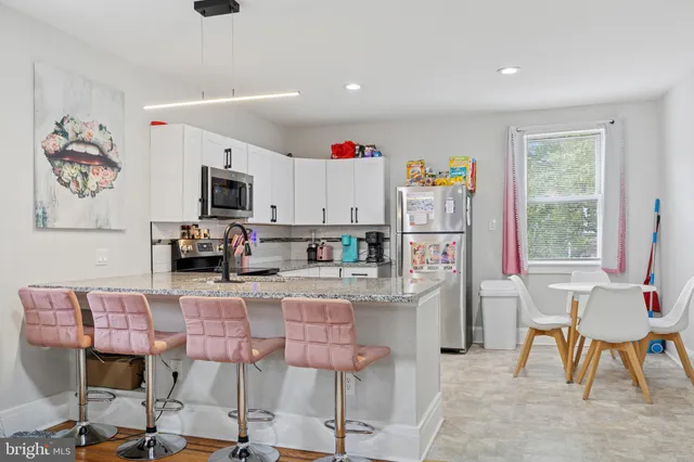 a living room with stainless steel appliances kitchen island a table and chairs in it