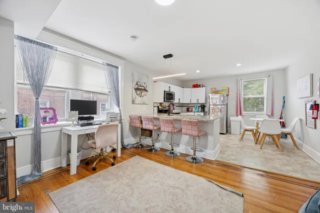 a living room with stainless steel appliances kitchen island granite countertop furniture and a wooden floor