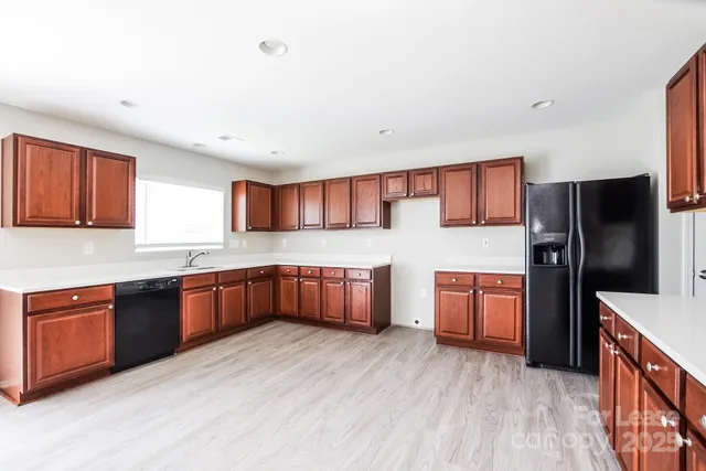 a kitchen with stainless steel appliances granite countertop a refrigerator a sink dishwasher a oven a dining table and chairs with wooden floor