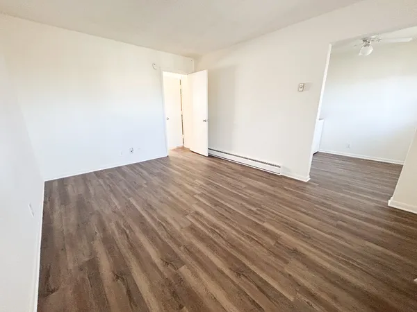 a view of an empty room with wooden floor and a window