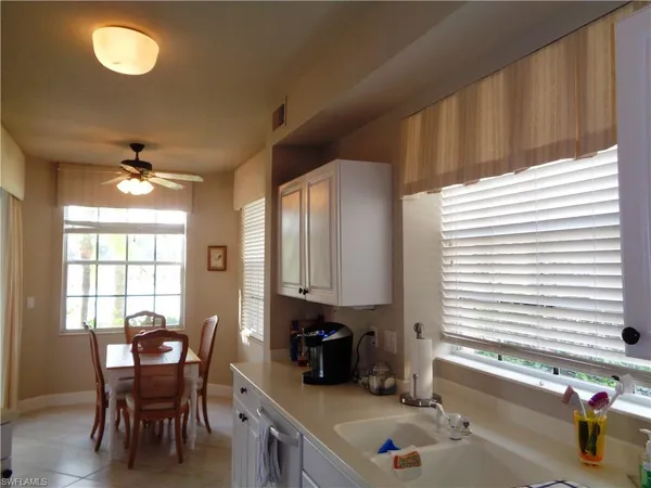a kitchen with stainless steel appliances granite countertop a stove a sink and a dining table with white cabinet