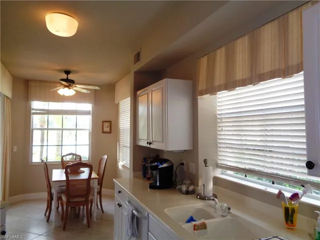 a kitchen with stainless steel appliances granite countertop a stove a sink and a dining table with white cabinet
