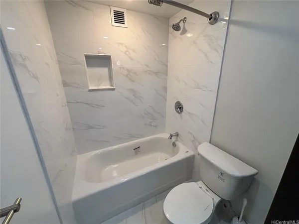 a white toilet sitting next to a bath tub