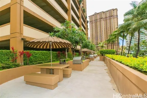 a patio with a table and chairs under an umbrella with a small garden
