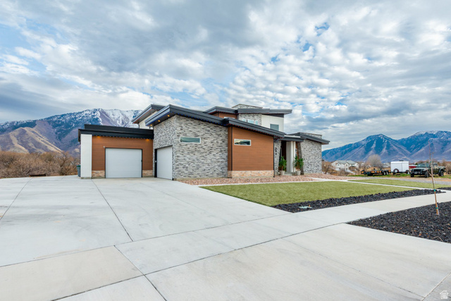262 North Santa Fe Drive Mapleton, UT 84664 - Photo 25 of 28 Modern home featuring a mountain view, stone siding, a garage, a front yard, and driveway