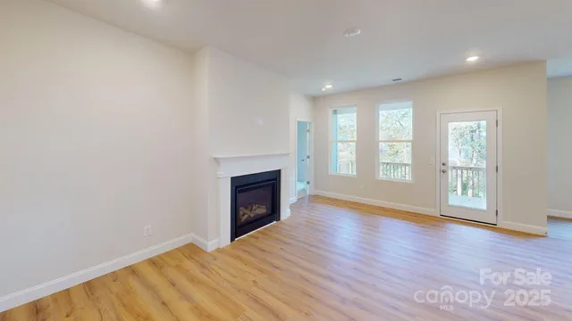 an empty room with wooden floor fireplace and windows