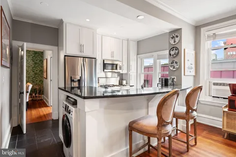 a dining table chair next to a window with kitchen view