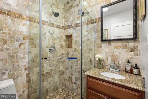 a bathroom with a granite countertop sink a mirror and shower