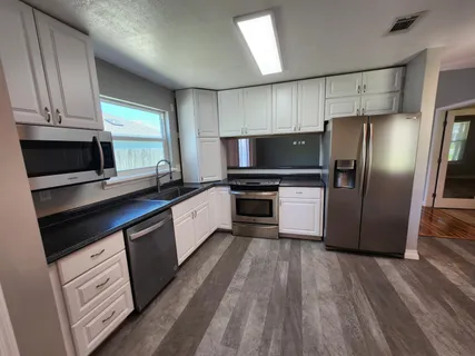 a kitchen with granite countertop a refrigerator microwave and sink