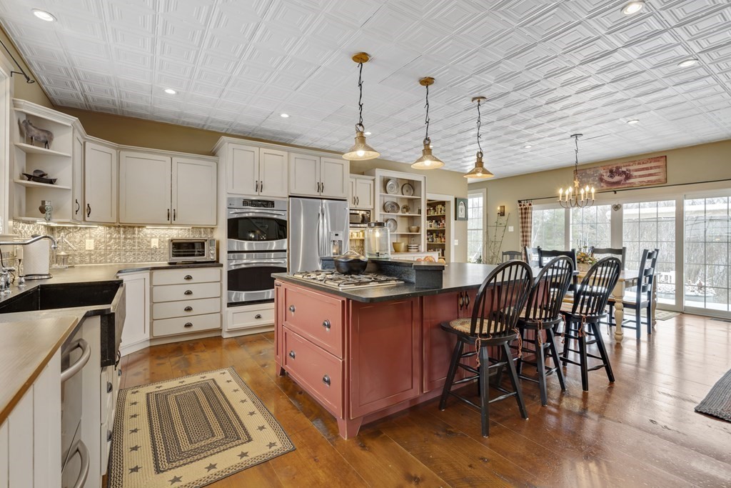 35 Piasta Road Dudley, MA 01571 - Photo 7 of 42 a kitchen with stainless steel appliances granite countertop a stove top oven a sink dishwasher a dining table and chairs with wooden floor