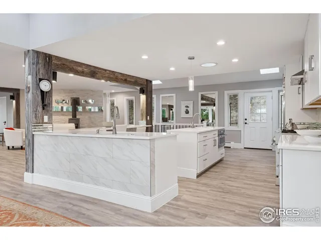 a large white kitchen with kitchen island a sink a counter top stainless steel appliances and cabinets