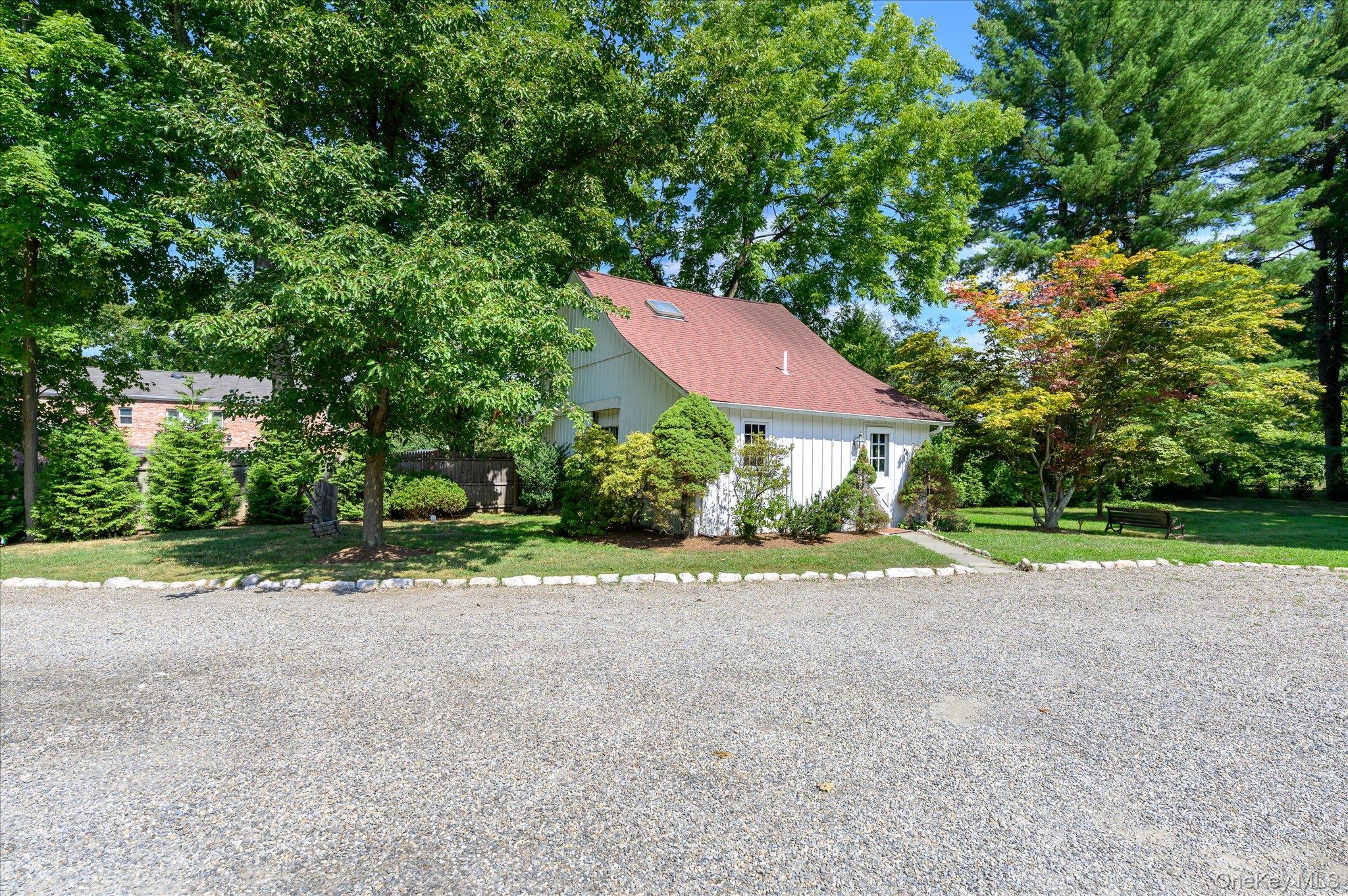 459 Old Post Road Bedford, NY 10506 - Photo 22 of 23 View of front facade with a front yard, a shingled roof, and view of wooded area