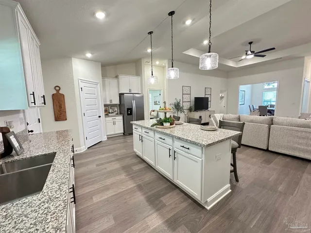 a large white kitchen with stainless steel appliances kitchen island granite countertop a lot of counter space and wooden floor