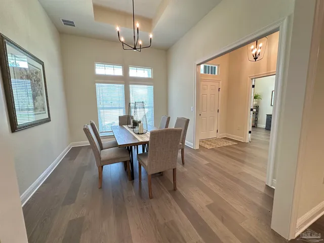 a dining room with wooden floor a chandelier a wooden table and chairs